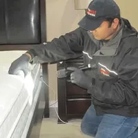 Bed bug inspection technician checking a mattress and bed frame for signs of infestation in Pembroke PInes, FL