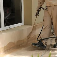 General pest control technician spraying exterior perimeter around a home in Pembroke PInes, FL