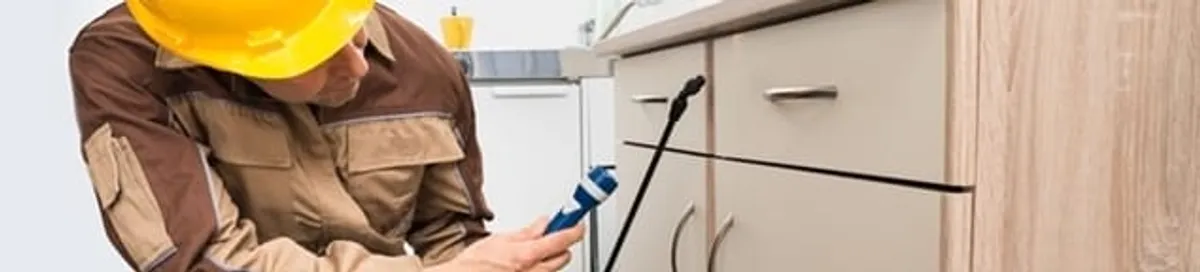 Roach exterminator applying treatment under kitchen cabinets in Pembroke PInes, FL