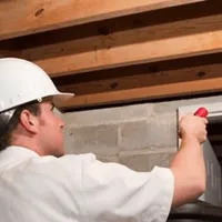 Termite inspection technician checking a basement wall and framing for termite activity in Pembroke PInes, FL